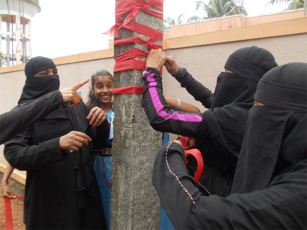 Women tying a red ribbon to an electric pole outside their gram panchayat's office as a symbol of the issues to be resolved.