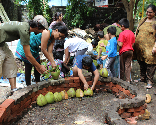 Children and adults create a 'raised bed' by putting a bottom layer of organic waste collected from the neighbourhood into a pit